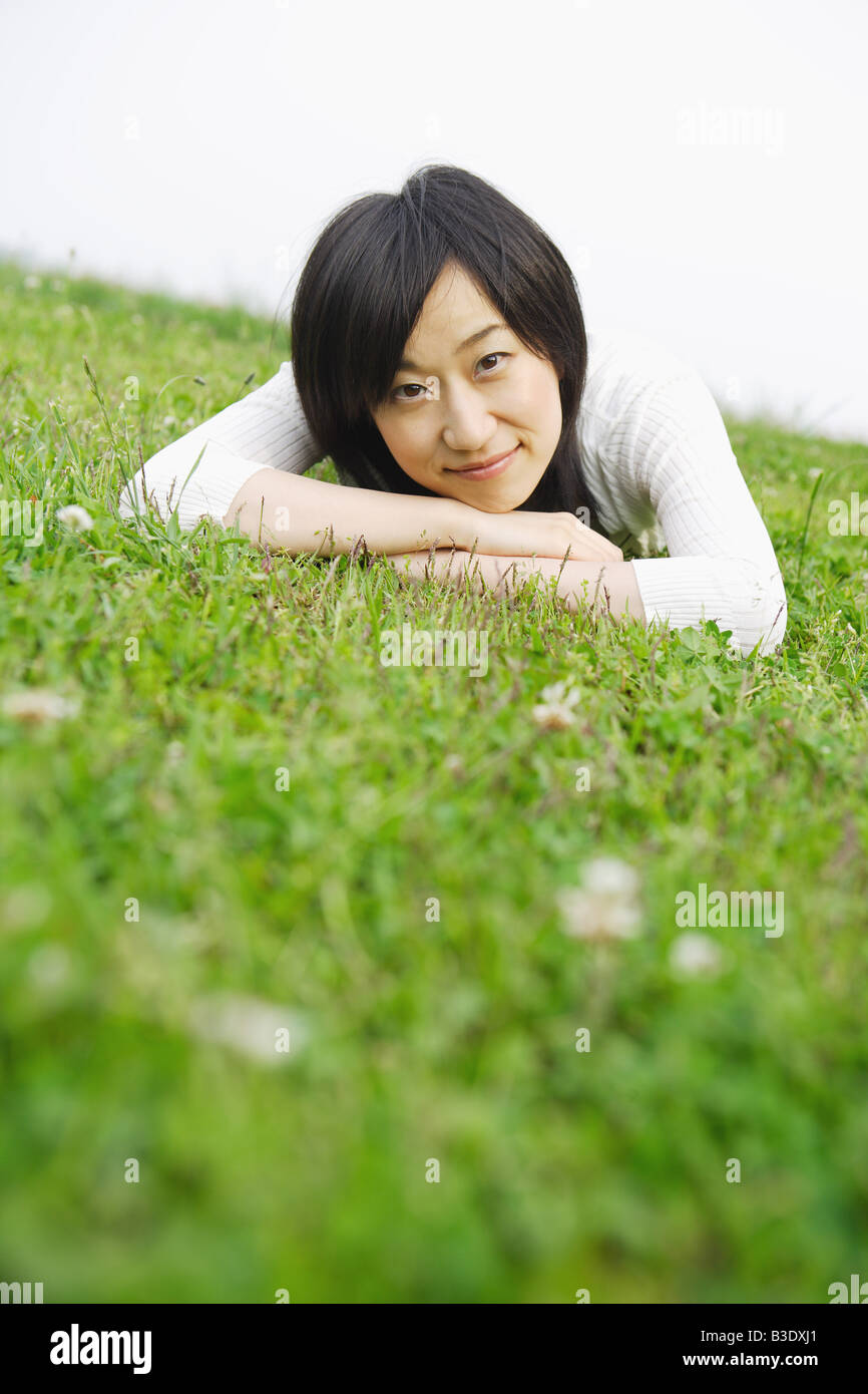 Junge lächelnde Frau liegend auf dem Rasen Stockfoto