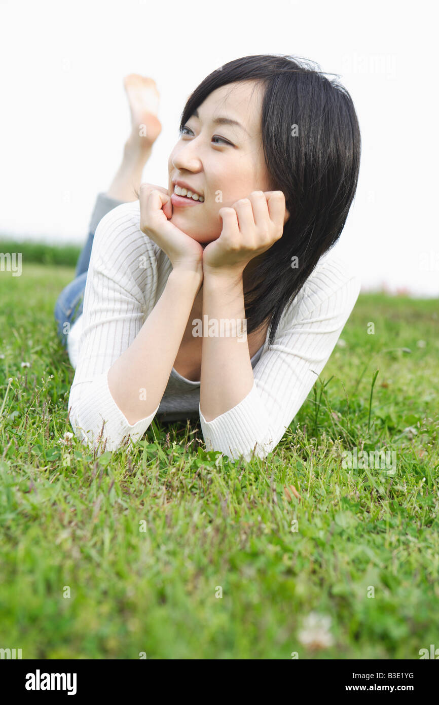 Junge lächelnde Frau liegend auf dem Rasen Stockfoto