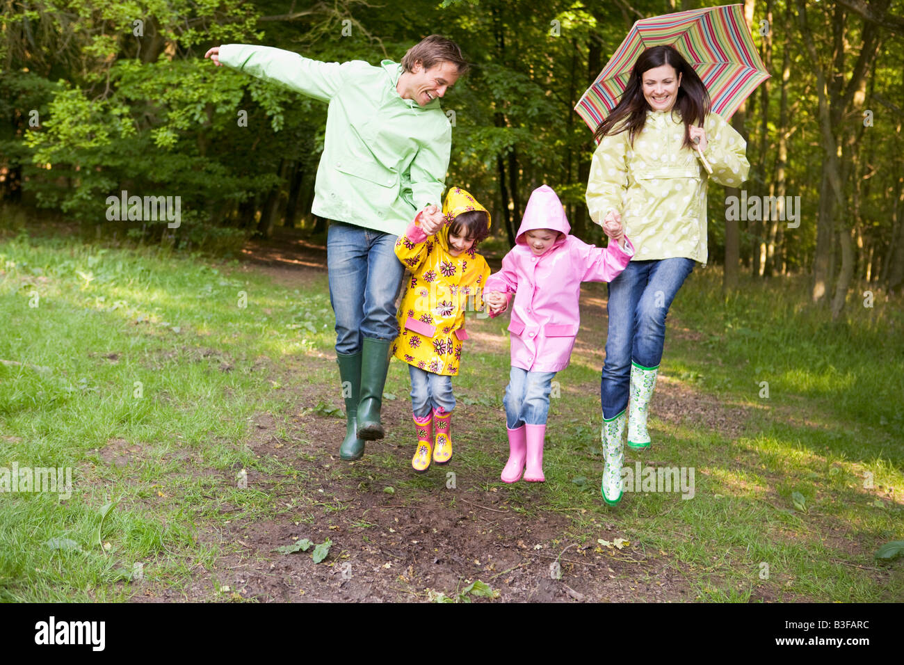 Familie im Freien mit Regenschirm lächelnden überspringen Stockfoto