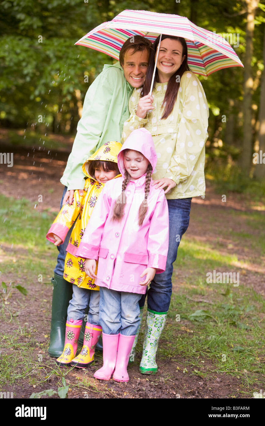 Familie im Freien bei Regen mit Regenschirm lächelnd Stockfoto