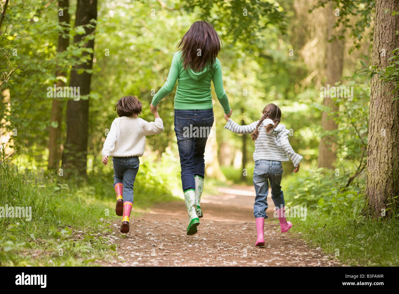 Mutter und Töchter auf Pfad lächelnd überspringen Stockfoto