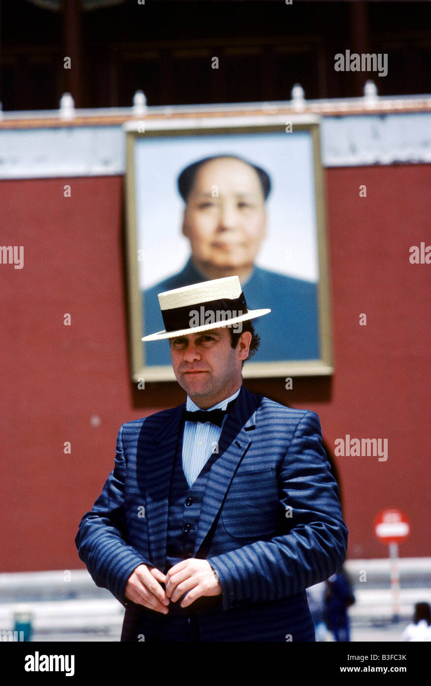 Britischer Pop-Sänger Elton John trägt einen Anzug, Fliege und Bootsfahrer am Tiananmen-Platz, mit Mao-Porträt im Hintergrund Stockfoto