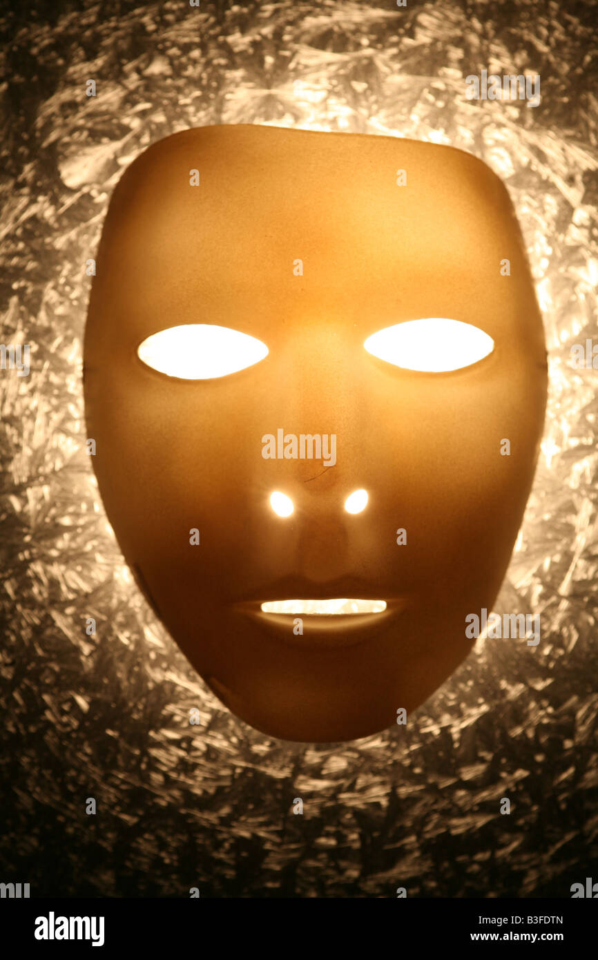 eine goldene Maske mit leuchtenden weißen Augen Stockfoto