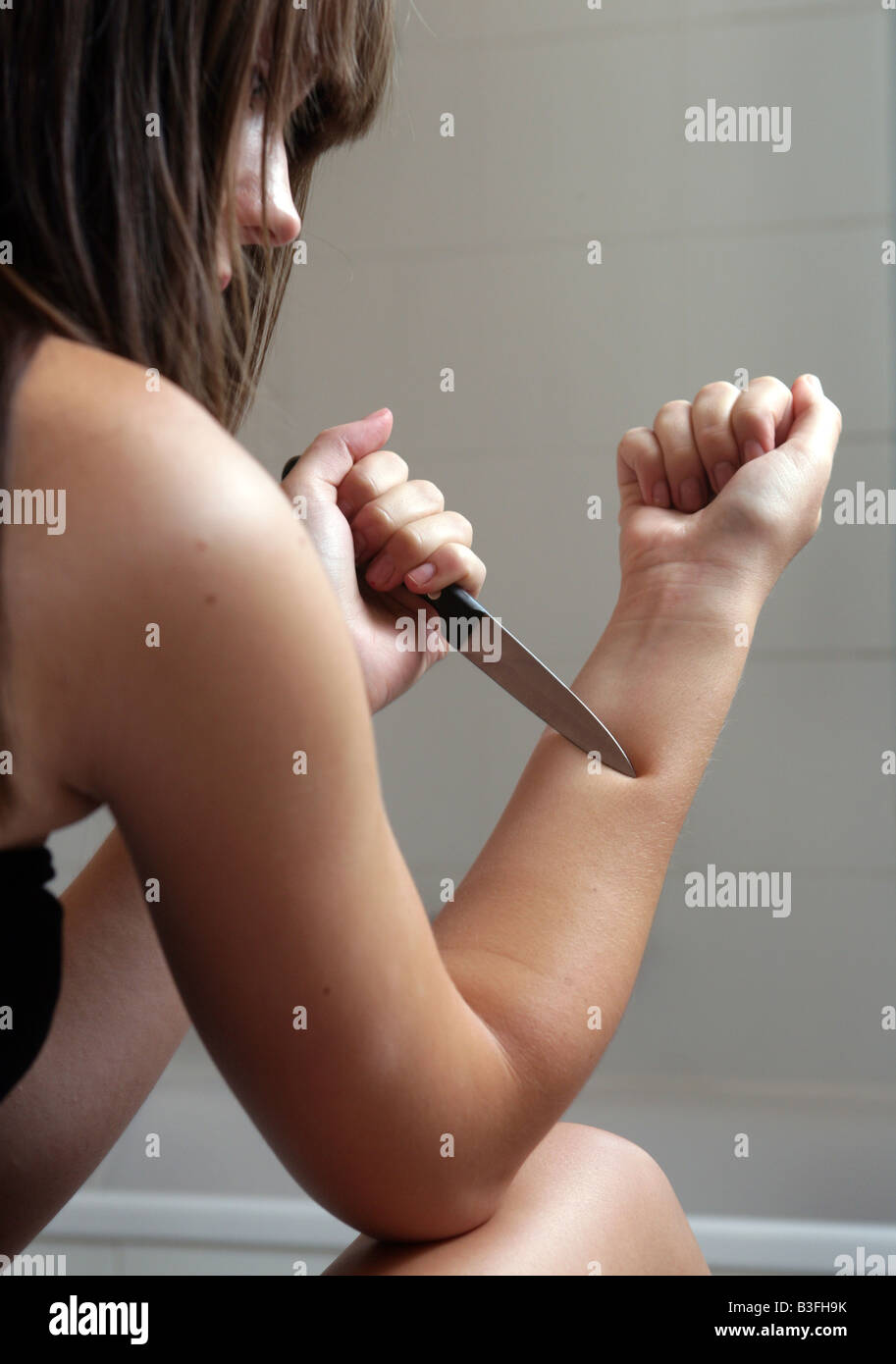 junge Frau verletzt sich selbst mit einem Messer Stockfoto