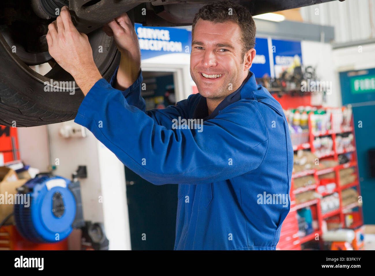 Mechaniker arbeiten unter dem Auto lächelnd Stockfoto