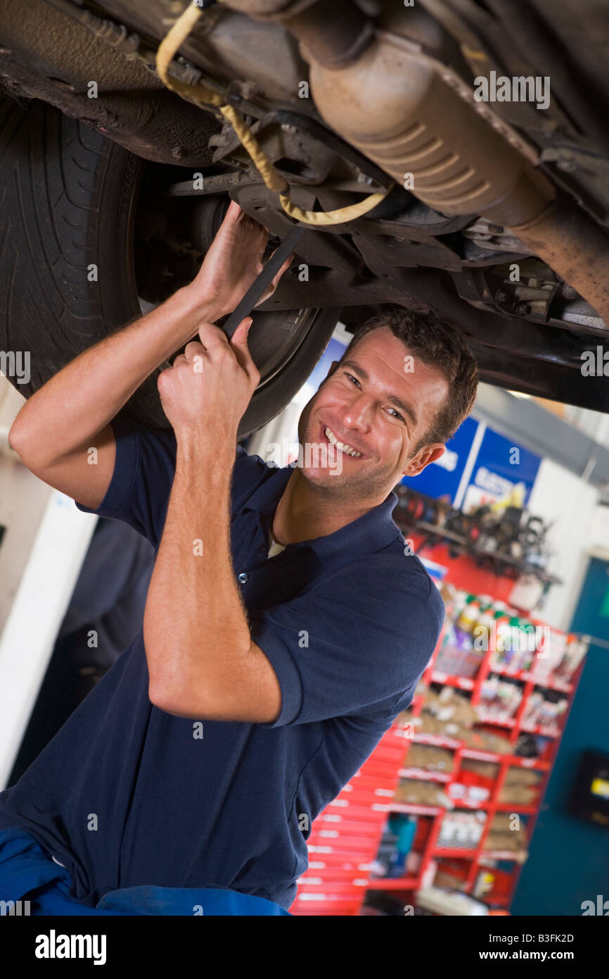 Mechaniker arbeiten unter dem Auto lächelnd Stockfoto