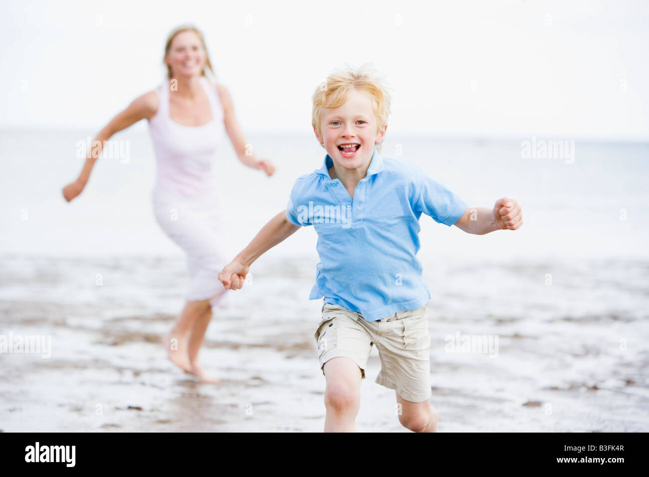 Mutter und Sohn am Strand lächelnd läuft Stockfoto