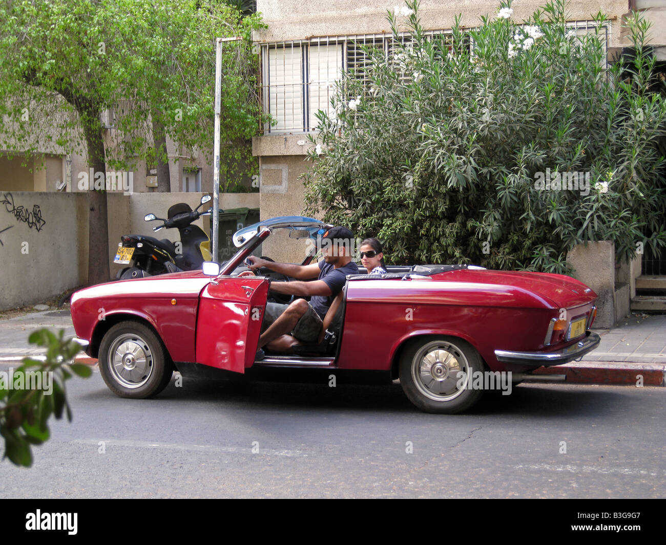 Jugendliche, ein altes Cabrio oder Cabriolet rotes Auto in der Innenstadt von Tel Aviv, Israel Stockfoto