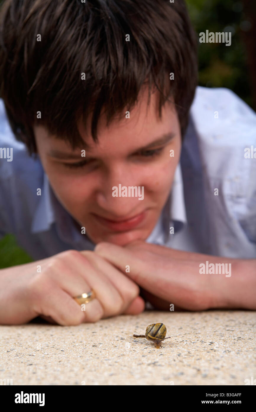 junge Erwachsene männliche Teenager auf der Suche auf eine Schnecke auf einer Gartenterrasse Stockfoto