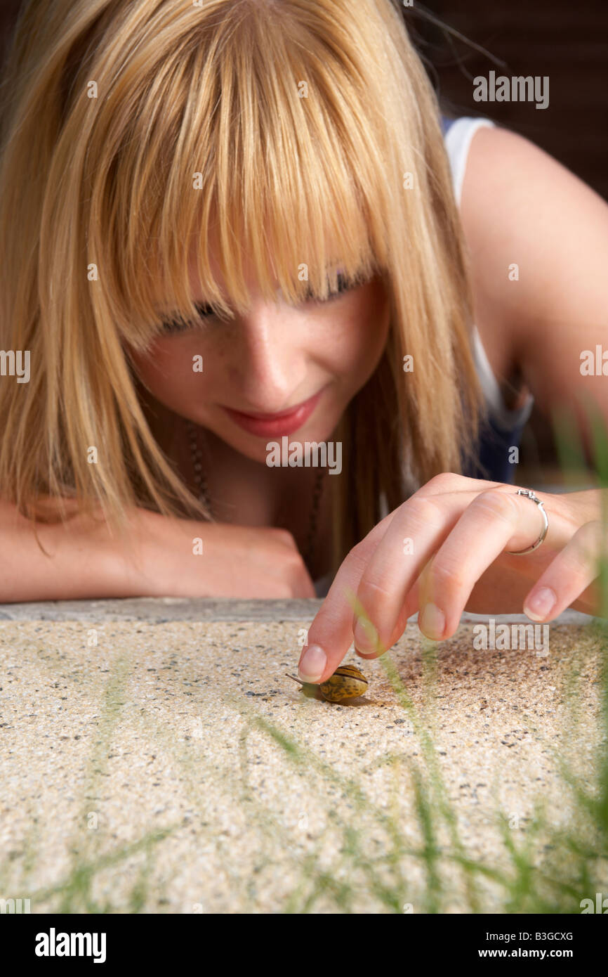 junge Erwachsene weibliche Teenager berühren und mit Blick auf eine Schnecke bewegt auf eine Gartenterrasse Stockfoto
