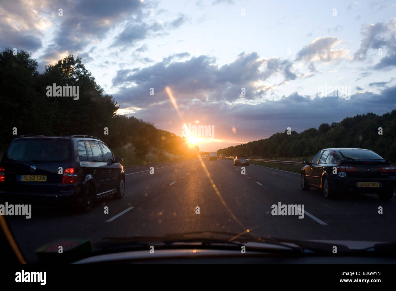 In einer untergehenden Sonne fahren beim Überholen auf der mittleren Spur westwärts Verkehr auf Kents M20 Autobahn Stockfoto