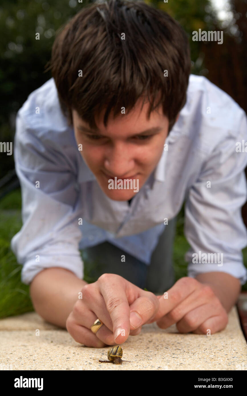 jungen Erwachsenen männlichen Teenager zeigt auf eine Schnecke auf einer Gartenterrasse Stockfoto
