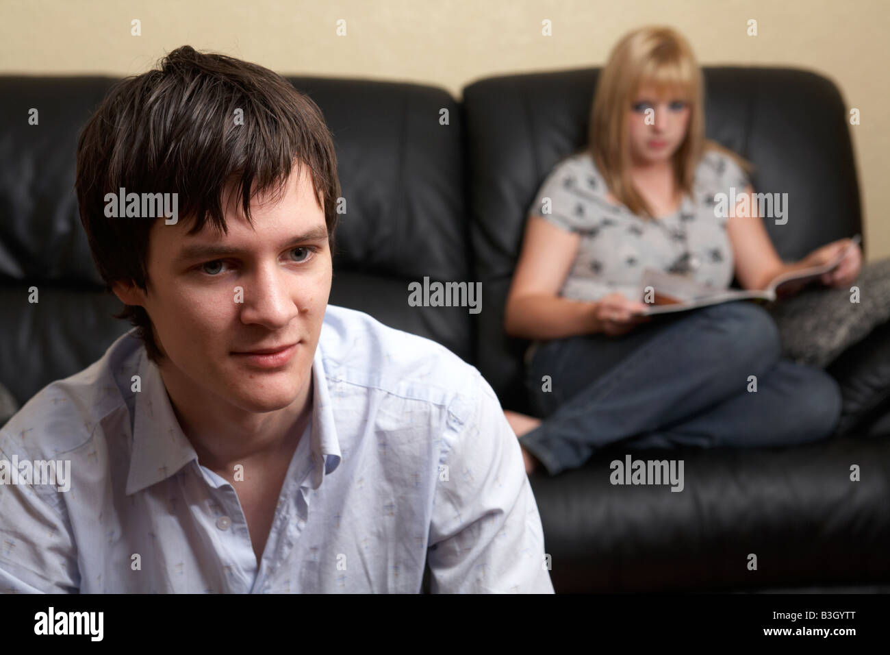 junger Mann und Frau Paar im Wohnzimmer sitzen gelangweilt Magazin lesen und geben einen bösen Blick Stockfoto