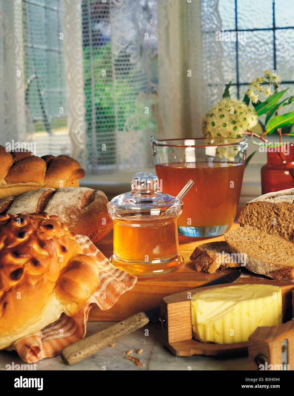 Stillleben mit Honig Glas mit frischem Brot und Butter auf Küchentisch Fenster. Stockfoto