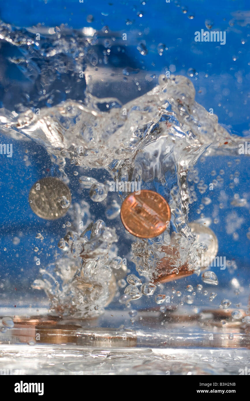Eine Handvoll Münzen fallen in etwas Wasser Stockfoto