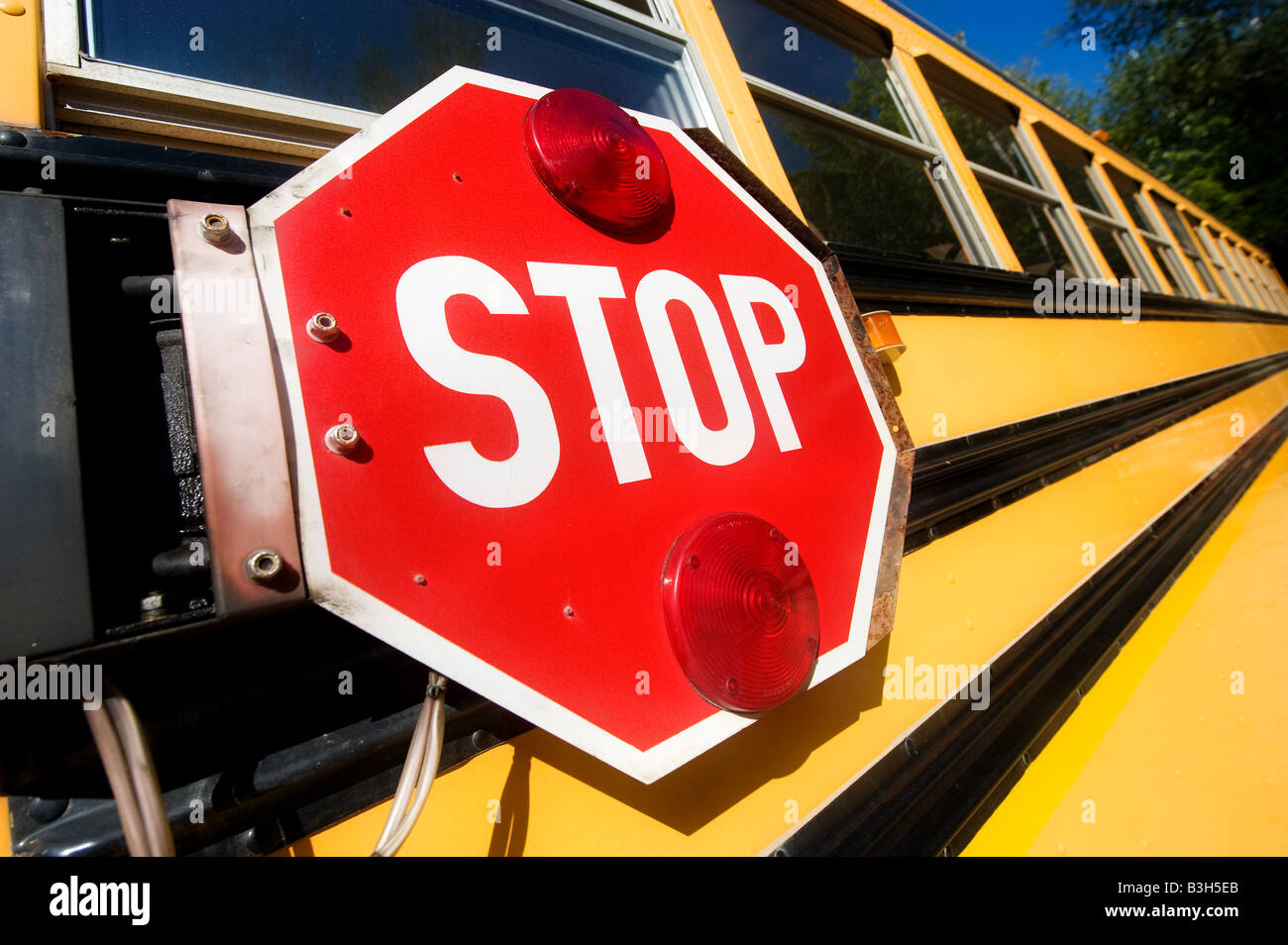 Das große rote Stoppschild signalisieren Arm an der Seite einen gelben Schulbus Autofahrer von Studenten zu warnen. Stockfoto