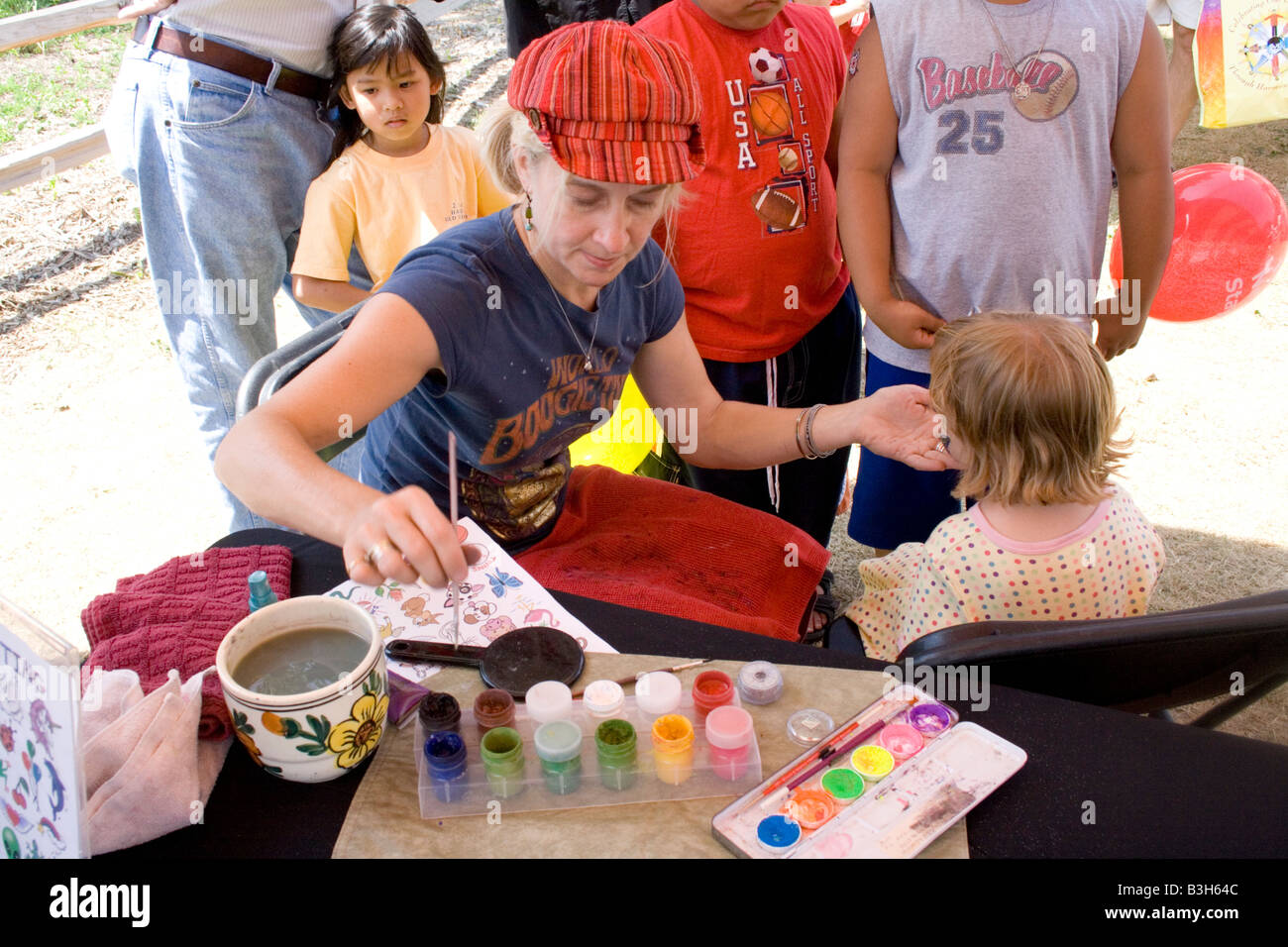 Gesicht Maler ihr Handwerk auf einem jungen Modell anzuwenden. Drachen-Festival Lake Phalen Park St. Paul Minnesota USA Stockfoto