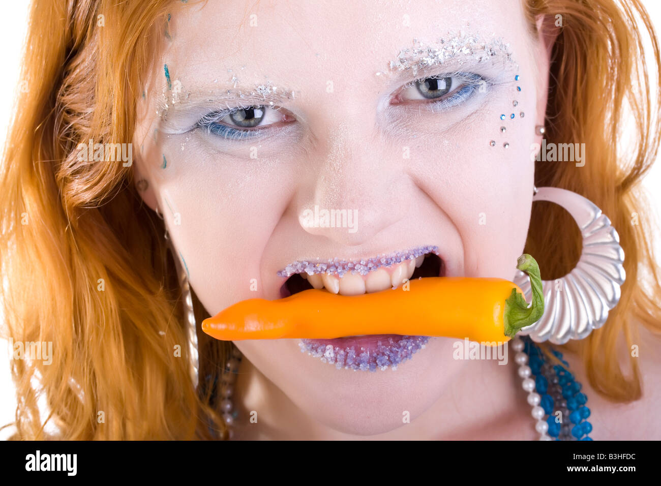 heiße rothaarige Frau mit Chili in Mund Stockfoto