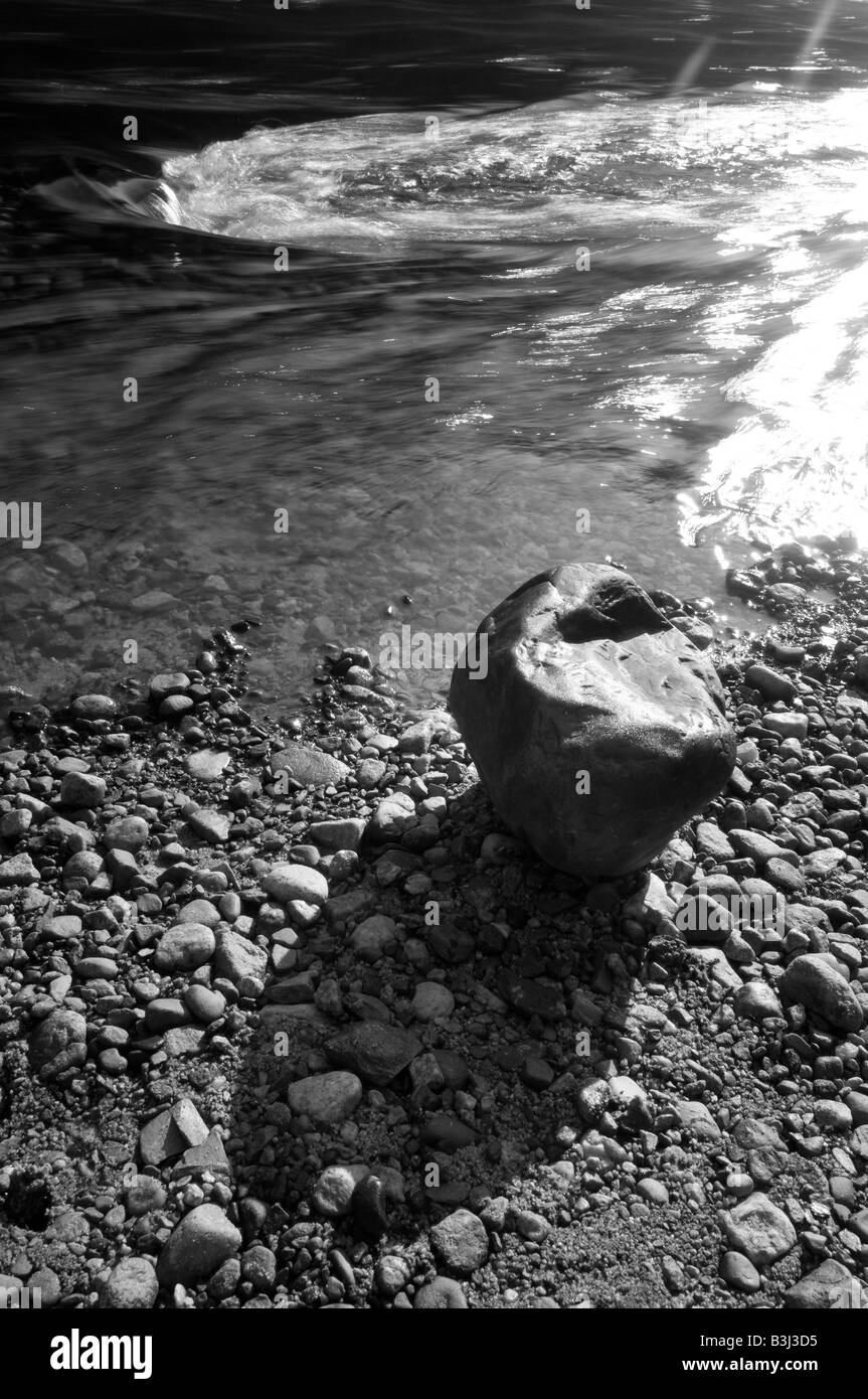 Einem großen Felsbrocken am Ufer eines schnell bewegten Flusses. Stockfoto