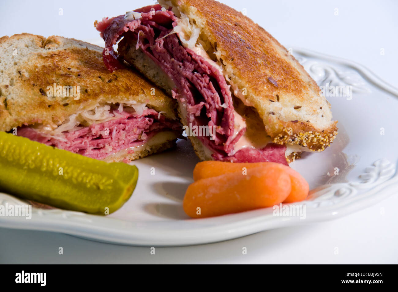 Reuben Sandwich mit einer Gurke und Karotten auf eine Weile Platte. Stockfoto