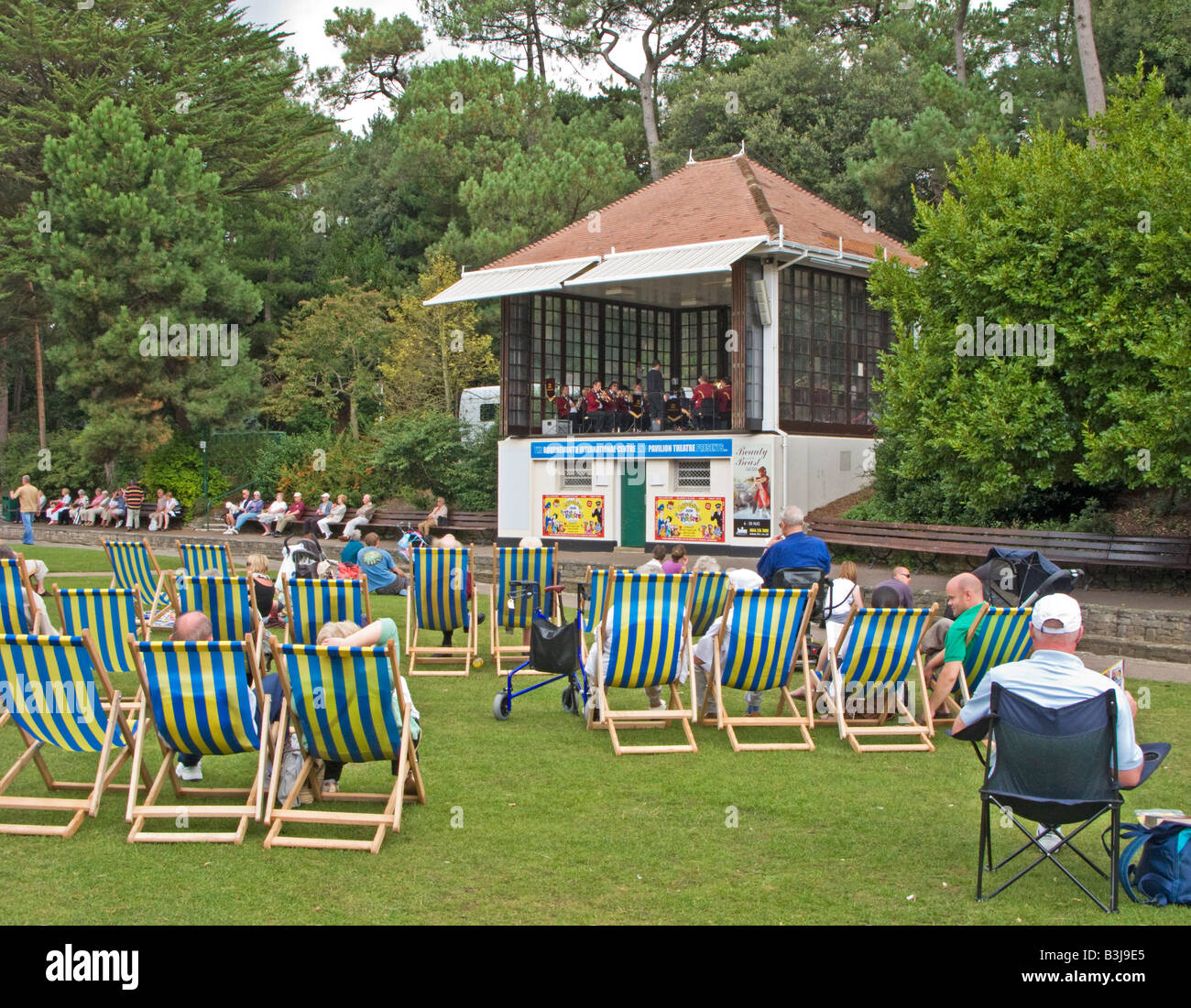 Menschen in Liegestühlen, die gerade ein Konzert in Bournemouth Gardens, Dorset, Großbritannien Stockfoto