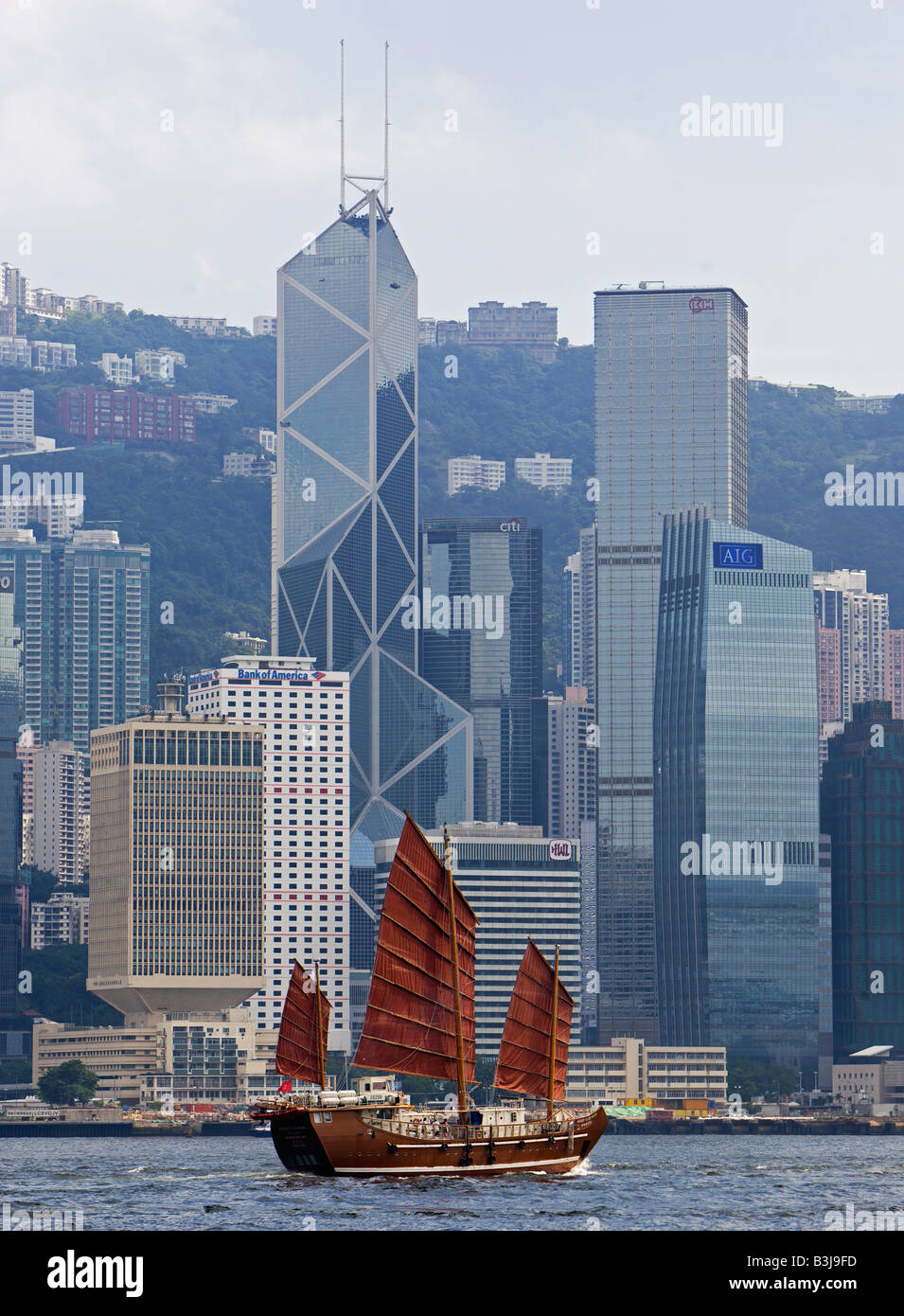 Traditionelle chinesische Dschunke, Segeln auf den Victoria Harbour mit der Hong Kong Skyline im Hintergrund Stockfoto