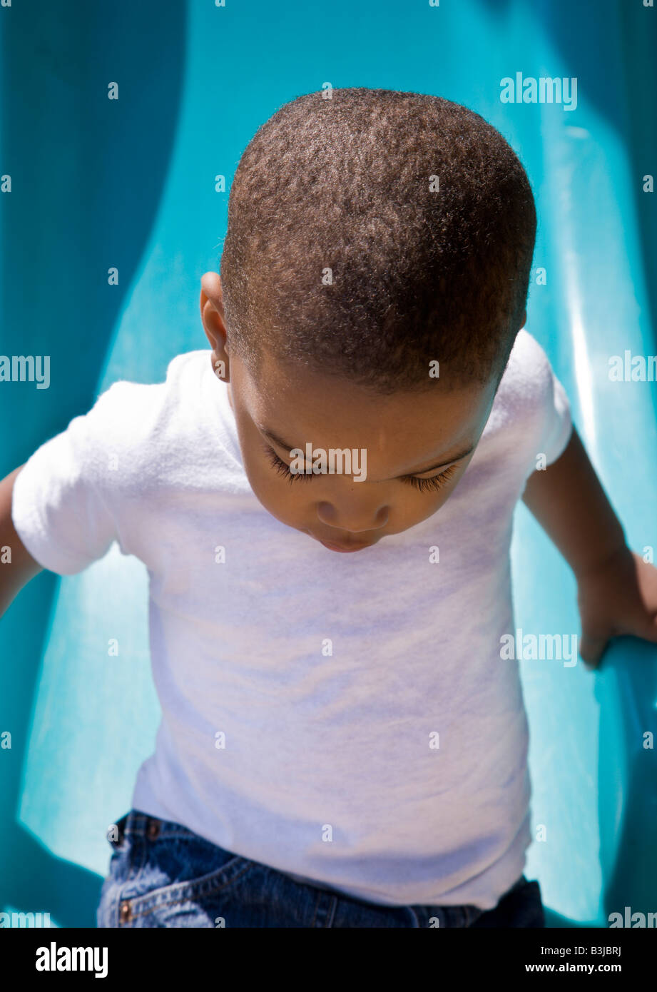 Ein 2 Jahre Alter African-American junge spielt auf einer Folie auf einem öffentlichen Spielplatz in Cathedral Square Park in Milwaukee, Wisconsin. Stockfoto