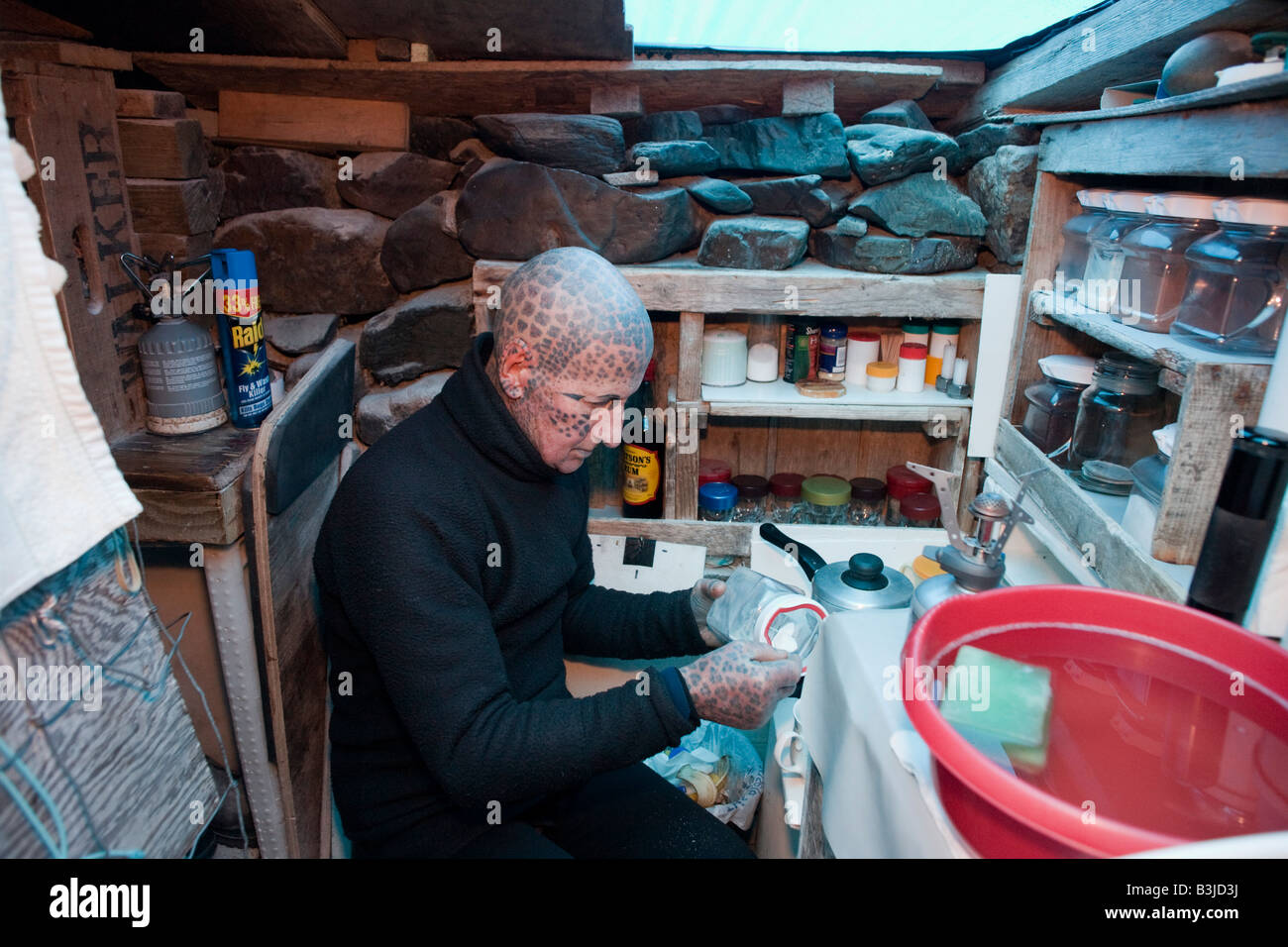 Tätowierte Einsiedler Tom Leppard (aka Leopard Mann) macht Tee in sein geheimes behelfsmäßigen unterirdischen Versteck Shelter auf Skye, Schottland Stockfoto