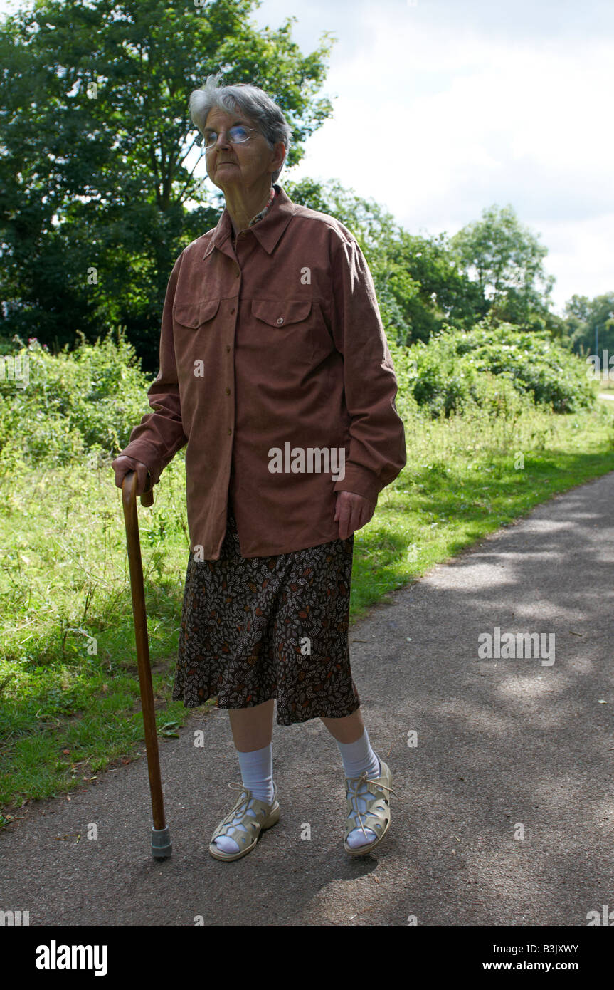 Ältere Frau (Schlaganfall leidende) gehen mit Stock Coe Fen Cambridge Stockfoto