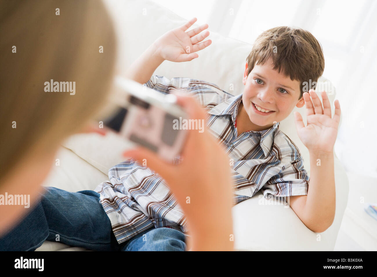 Junges Mädchen unter Bild des lächelnden jungen mit Kamera-Handy im Innenbereich Stockfoto