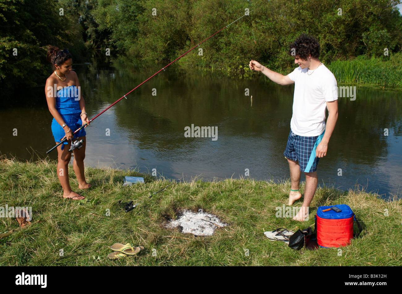 Junge Menschen, die Spaß und posiert für die Kamera mit einem Fisch gefangen er am Fluss Cam zwischen Cambridge und Grantchester Stockfoto