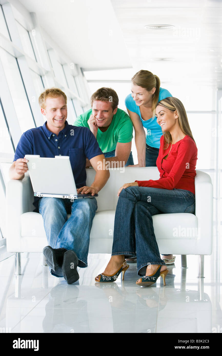 Vier Menschen in Lobby Blick auf Laptop lächelnd Stockfoto
