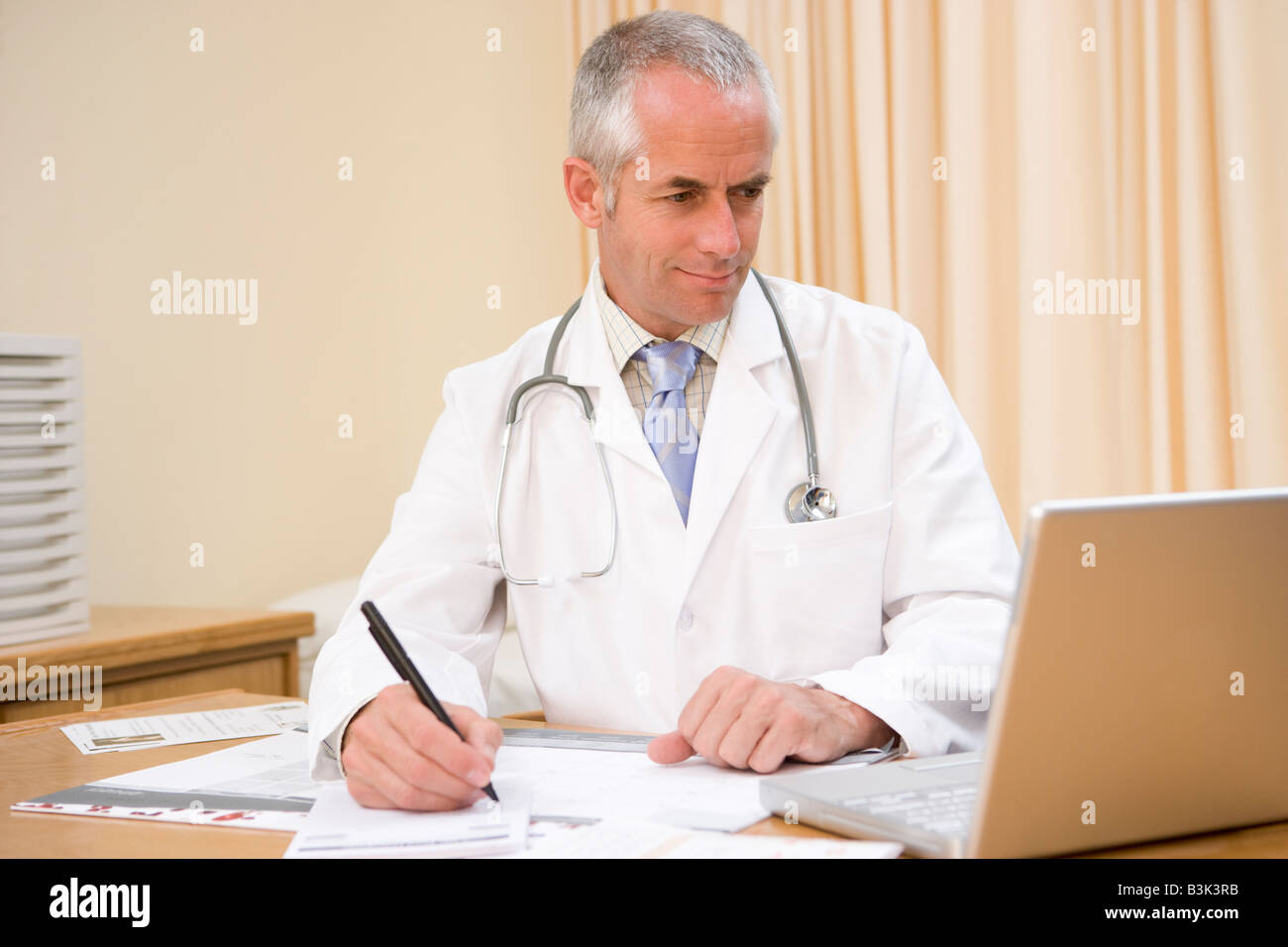 Arzt mit Laptop und schreiben in Arztpraxis Stockfoto