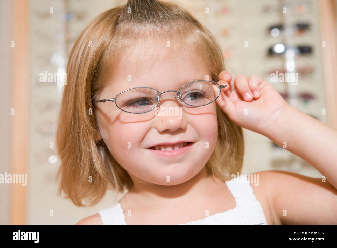 Junge Mädchen versuchen auf Brillen beim Optiker lächelnd Stockfotografie Alamy