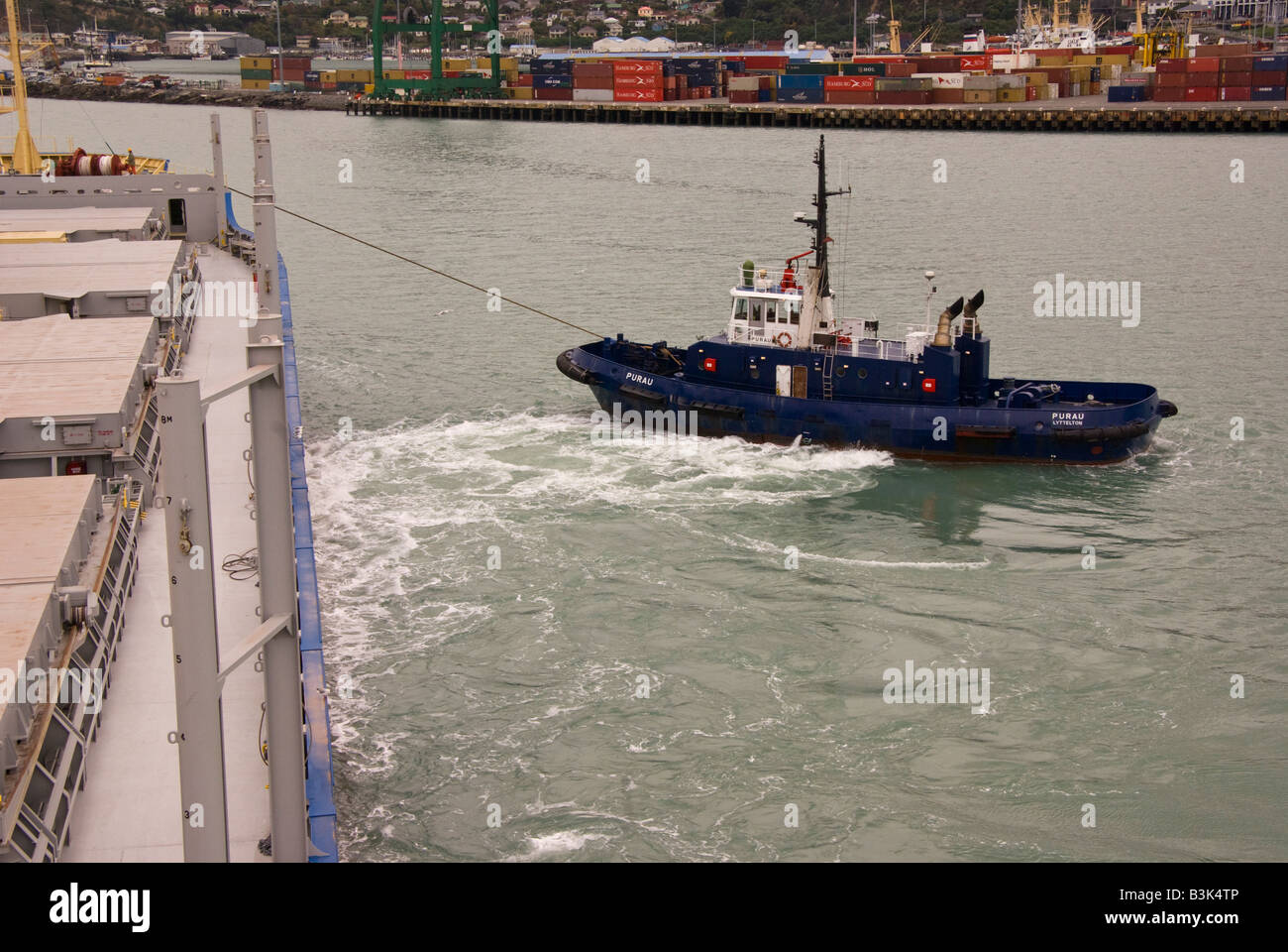 Ein Schlepper hilft ein Schiff bei seiner Ankunft im Hafen an der Lyttelton, Neuseeland zu drehen Stockfoto