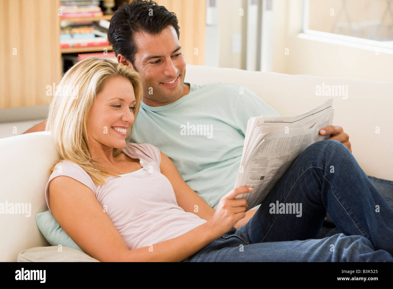Paar im Wohnzimmer Zeitung lesen und Lächeln Stockfoto
