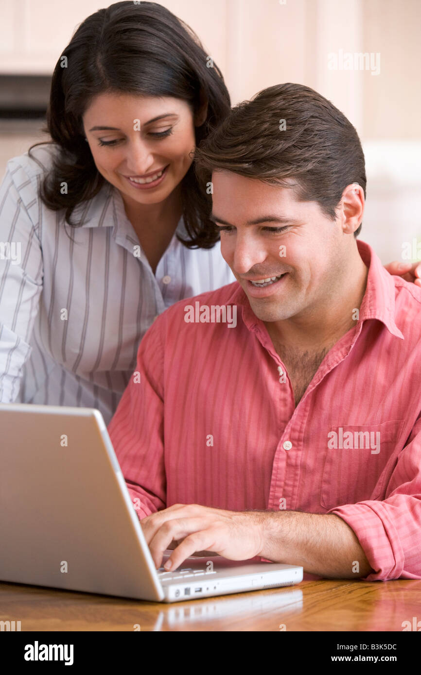 Paar in der Küche mit Papierkram mit Laptop lächelnd Stockfoto