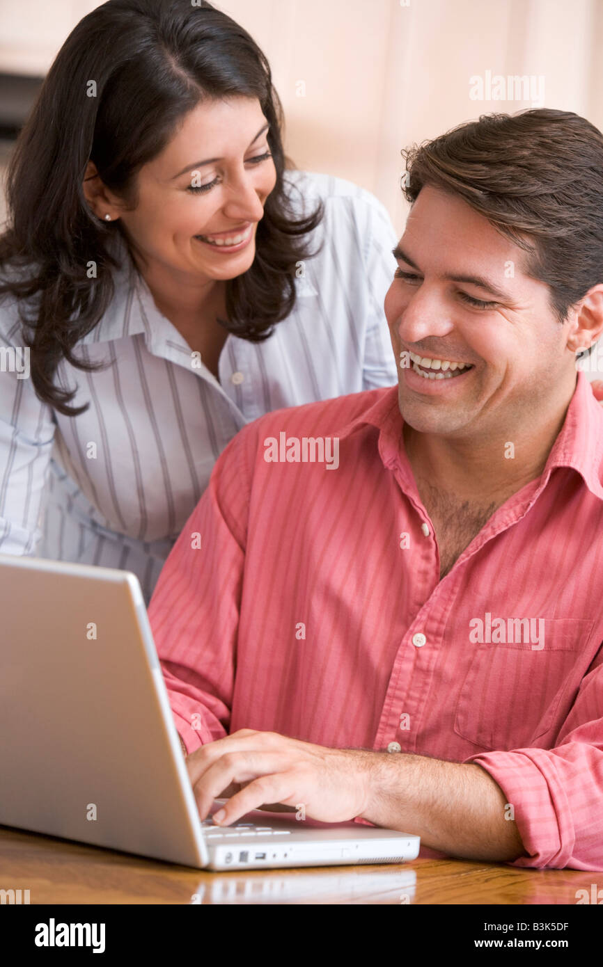 Paar in Küche mit Laptop lächelnd Stockfoto