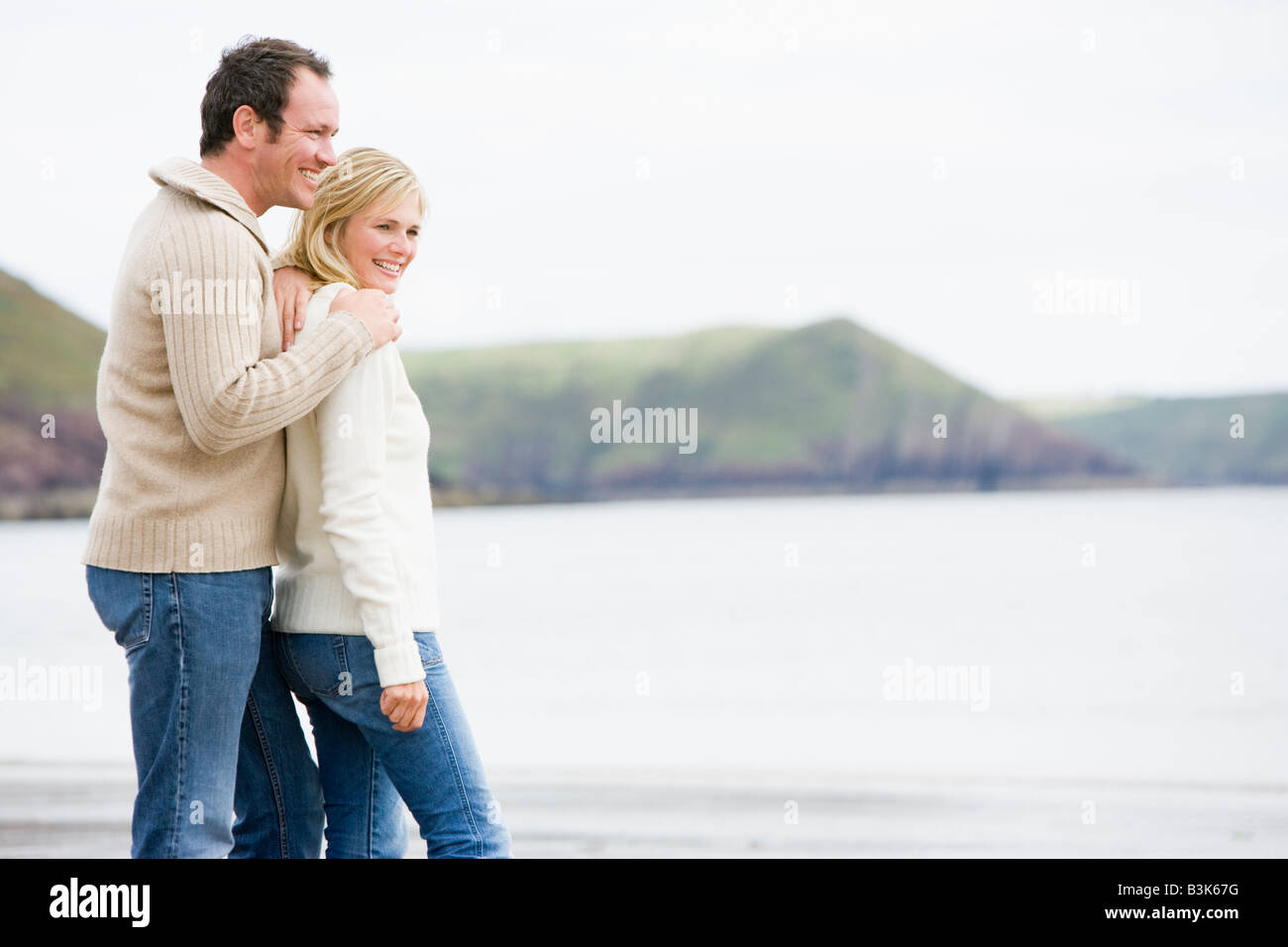 Paar steht am Strand lächelnd Stockfoto