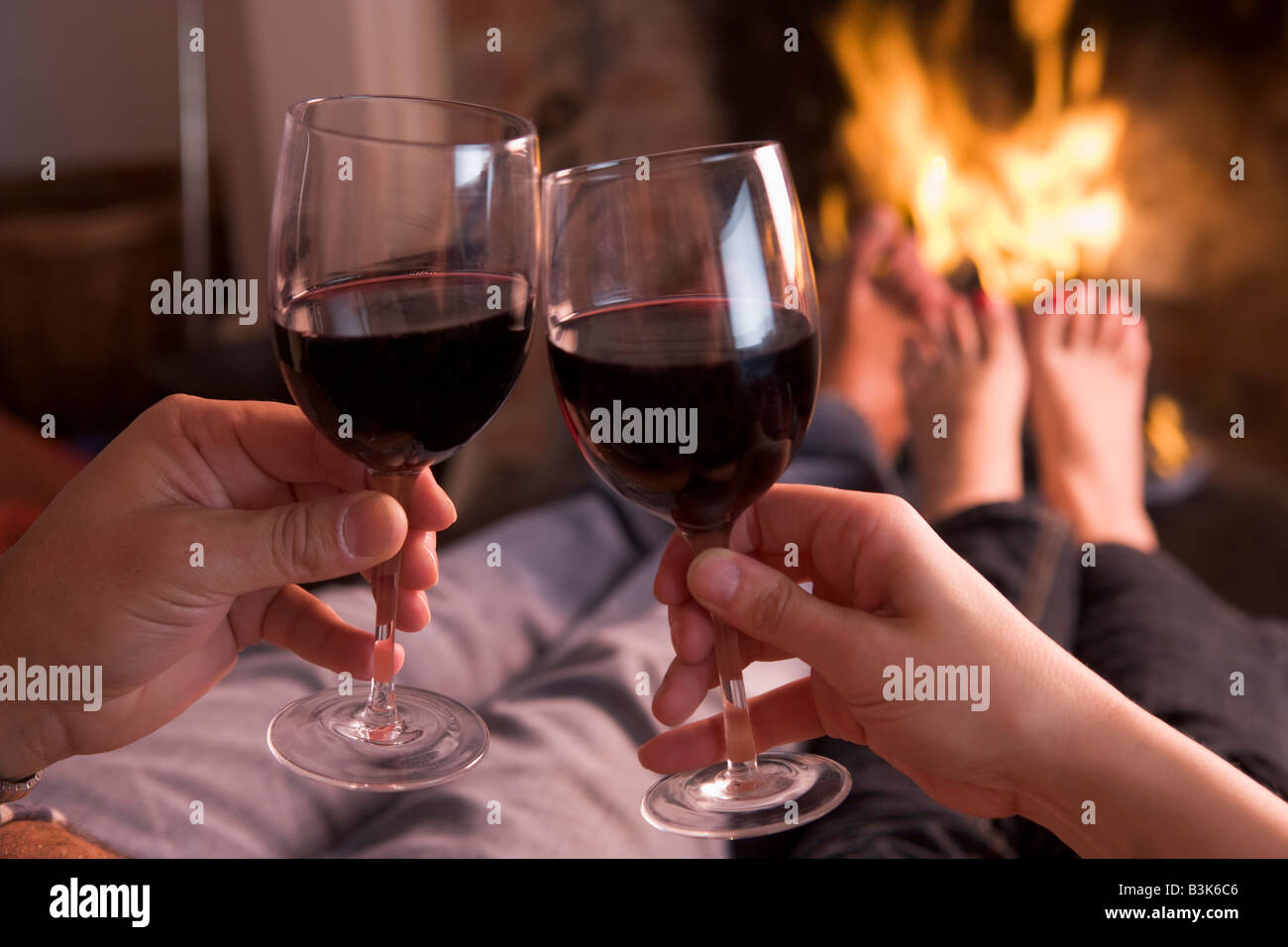 Füße mit Händen mit Wein am Kamin Erwärmung Stockfoto