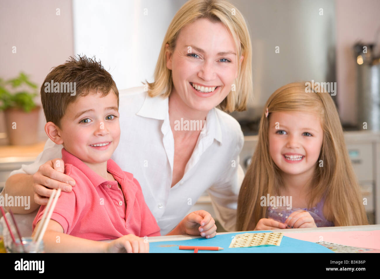 Frau und zwei kleinen Kindern in Küche mit Kunst Projekt lächelnd Stockfoto