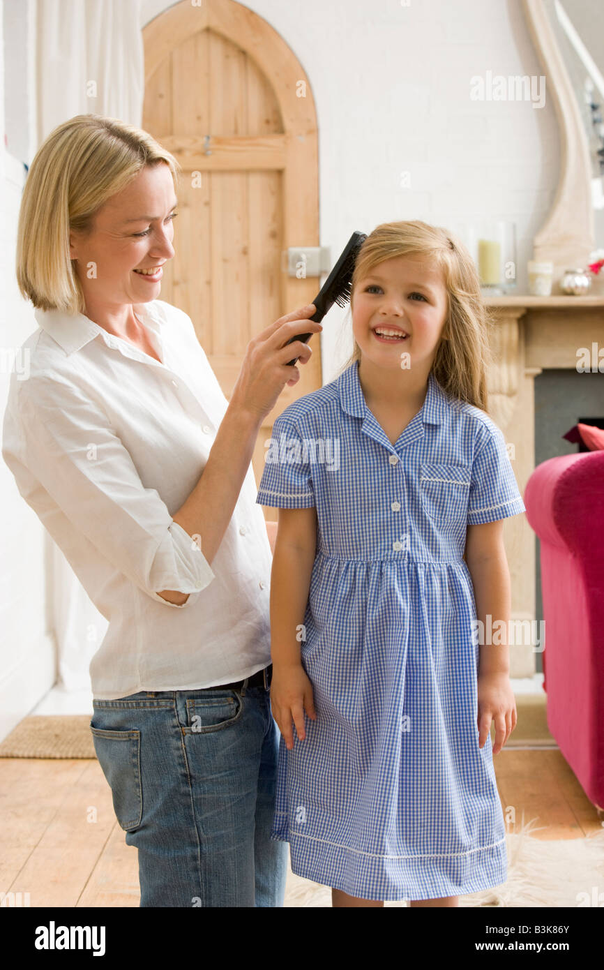 Frau im vorderen Flur putzen junge Mädchen an den Haaren und lächelnd Stockfoto