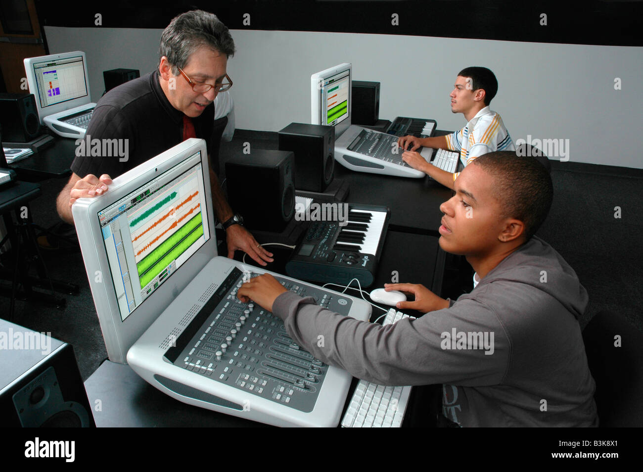 Schüler arbeiten mit computergesteuerten Audio Mischpulten mit einem Lehrer, die Aufsicht über Stockfoto