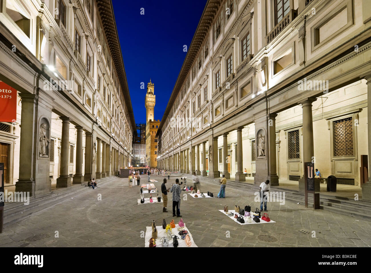 Illegale Straßenverkäufer ausserhalb der Uffizi Galerie in der Nacht mit dem Palazzo Vecchio in der Ferne, Florenz, Toskana, Italien Stockfoto
