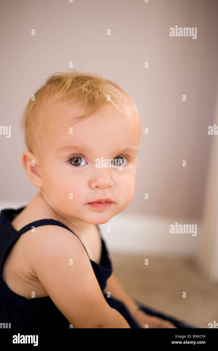 Porträt von acht Monate altes Baby Mädchen sitzend, Blick in die Kamera Stockfoto
