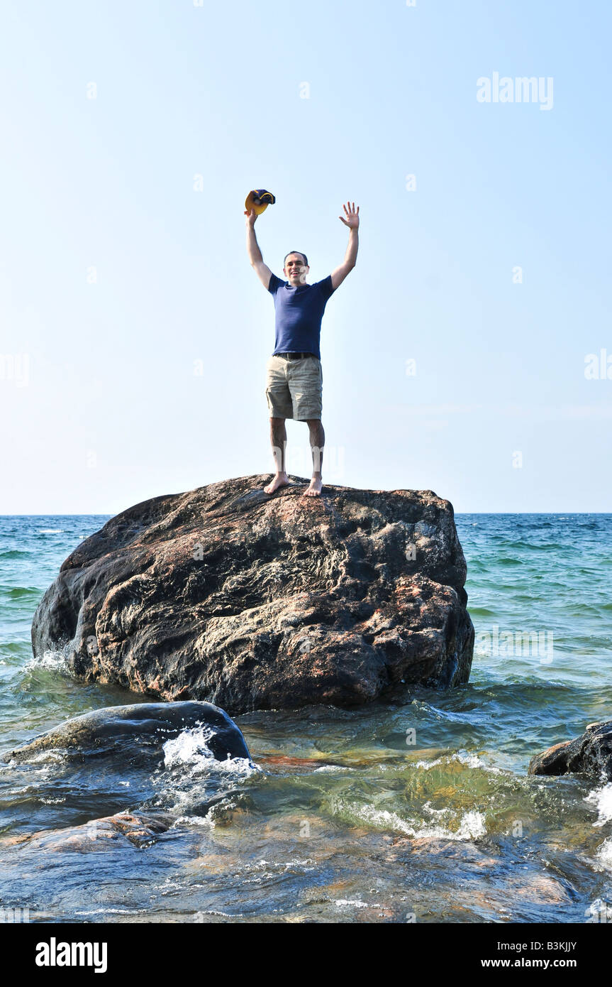 Mann, gestrandet auf einem Felsen im Meer um Hilfe rufen Stockfoto