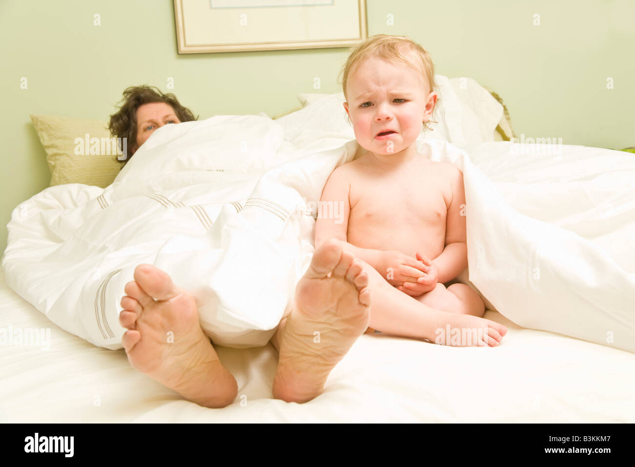 Baby weint neben Mutter im Bett Stockfoto