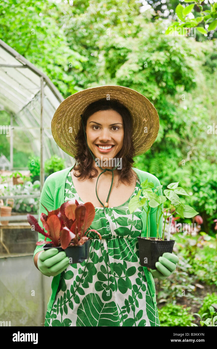 Frau Holding Pflanzen im Garten Stockfoto