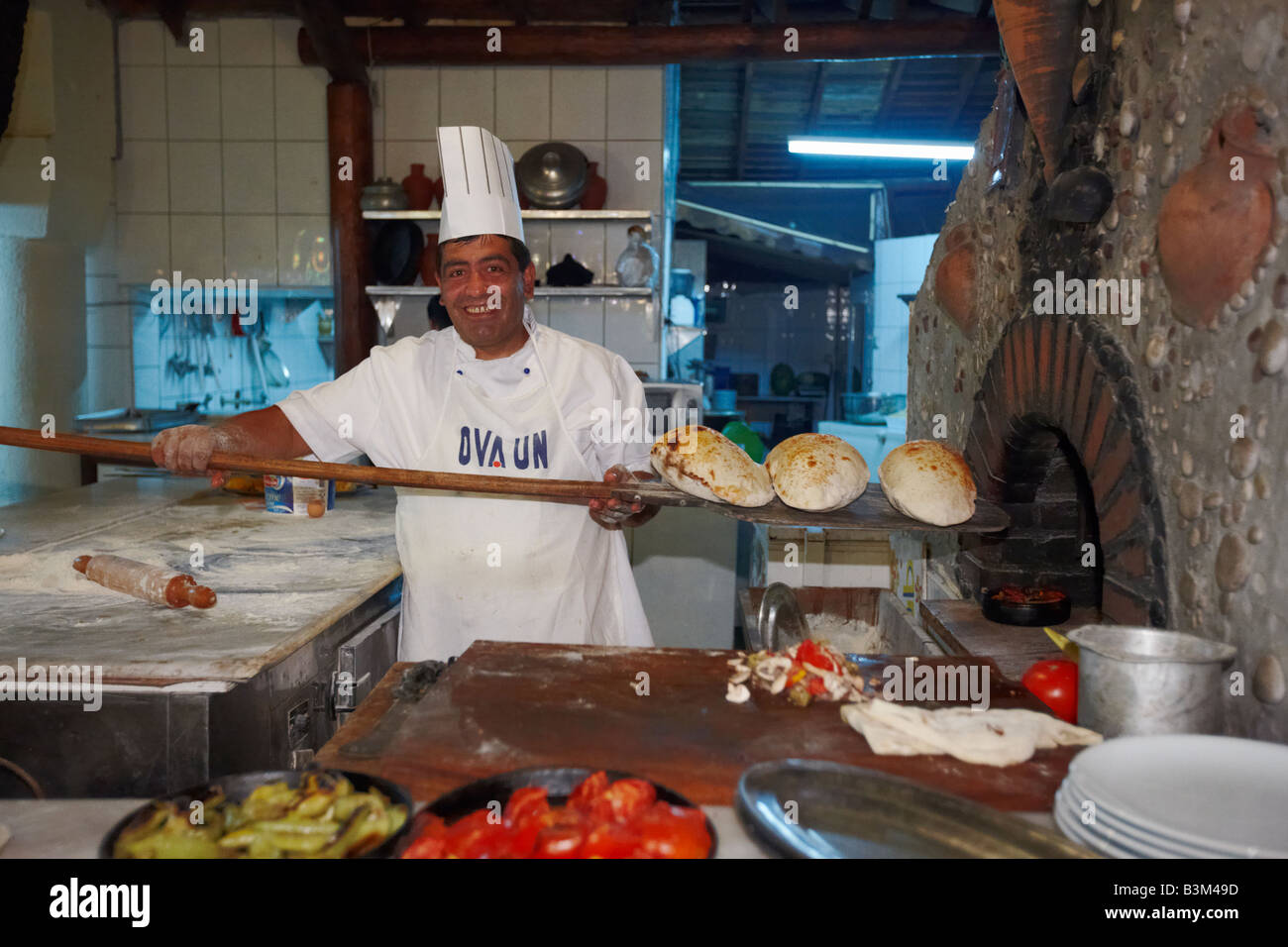 Chef Baker Holding eine hölzerne Schale mit frisch gebackenem Brot in Sultan Ahmet, traditionelles türkisches Restaurant. Ölüdeniz Village, Provinz Mugla, Türkei. Stockfoto