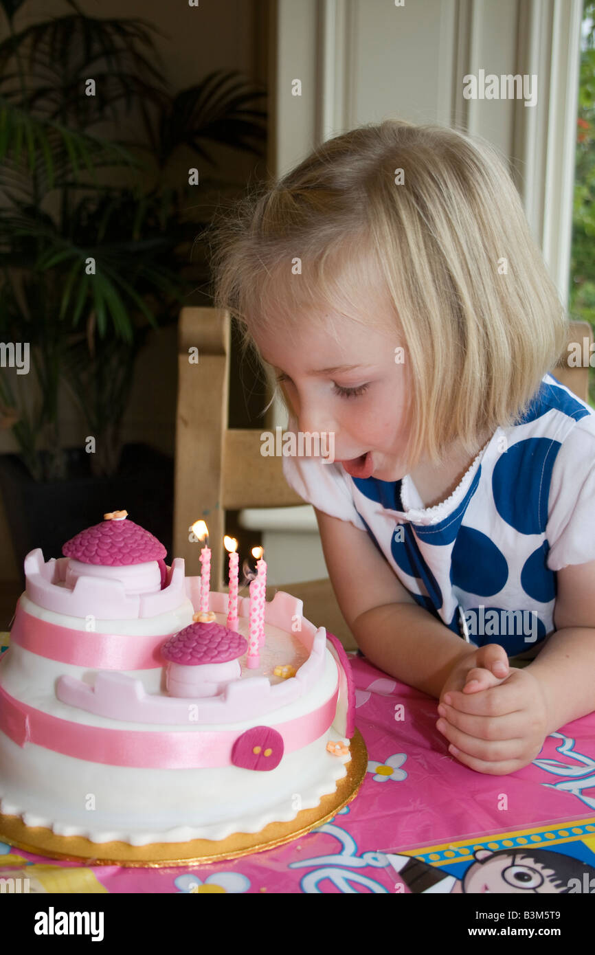 UK 4 Einjahresmädchen Ausblasen der Kerzen auf der Geburtstagstorte Stockfoto